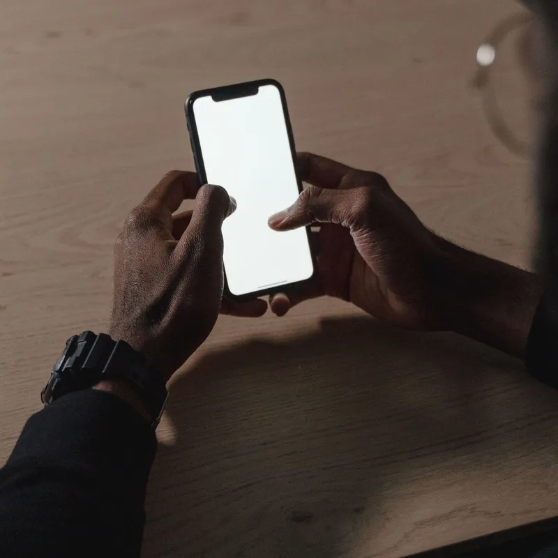 Illustrative photograph — a person using a phone at a kitchen table