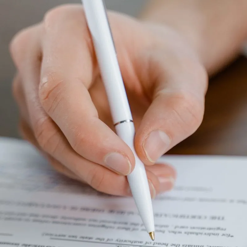 Illustrative photograph — hands and a pen over a document