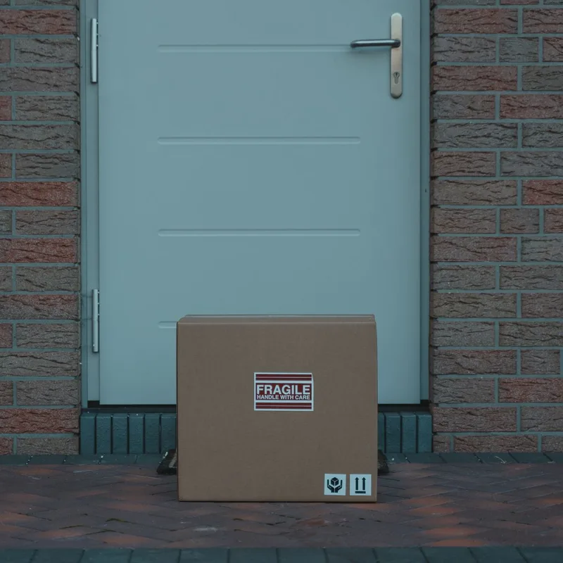 Illustrative photograph — a plain parcel being handed over on a doorstep